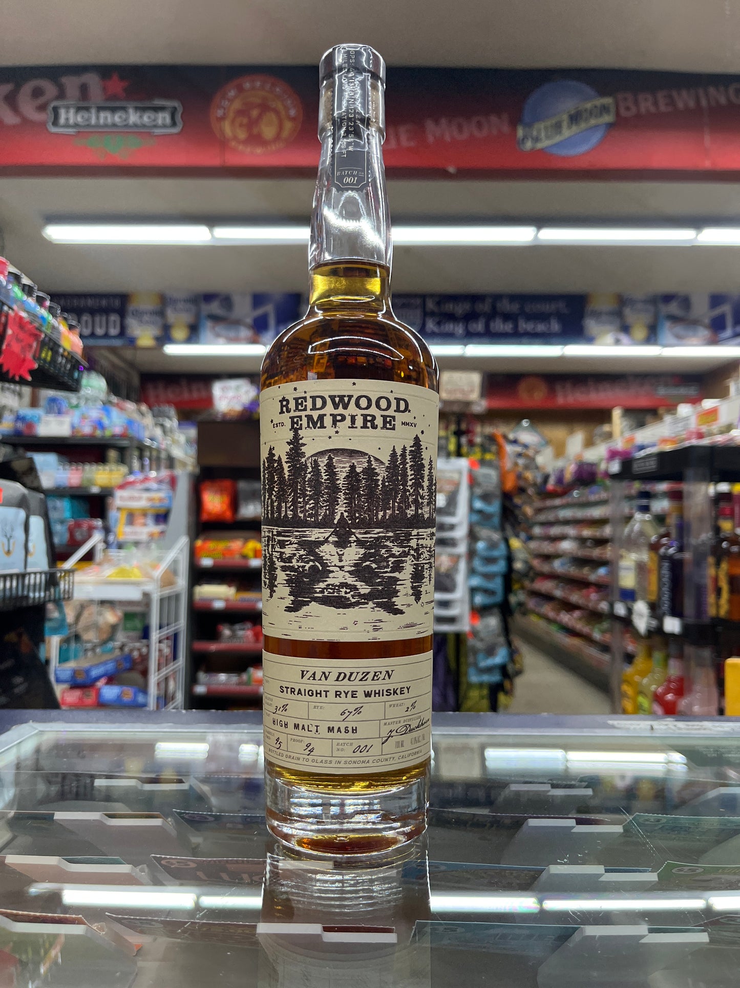 A bottle of Redwood Empire Van Duzen Straight Rye Whiskey positioned in front of a shelf with various alcoholic beverages in the background.