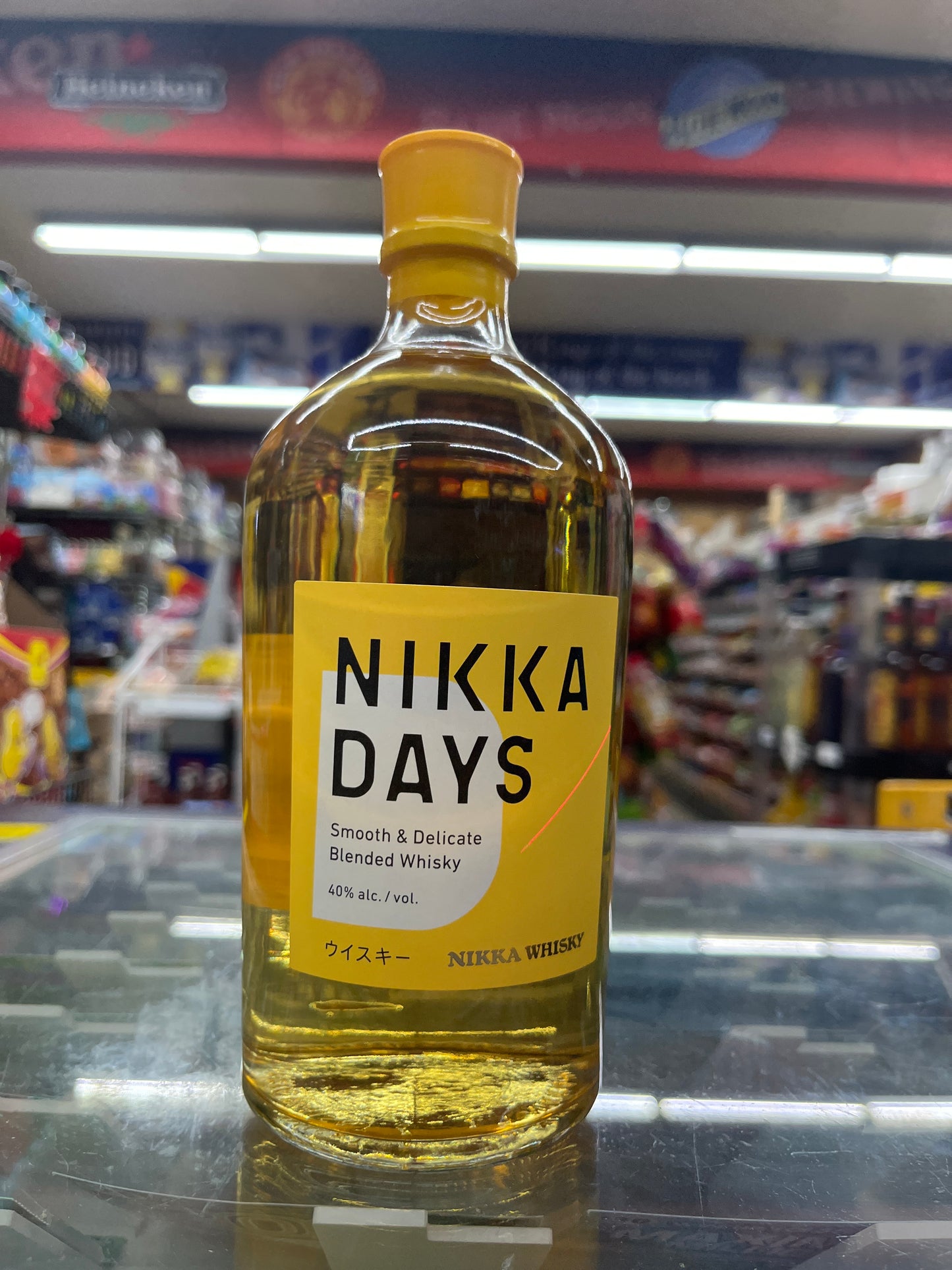 A bottle of Nikka Days Smooth & Decadent Japanese Whisky, 750ml, with a yellow label and cap, displayed on a shelf in a store.