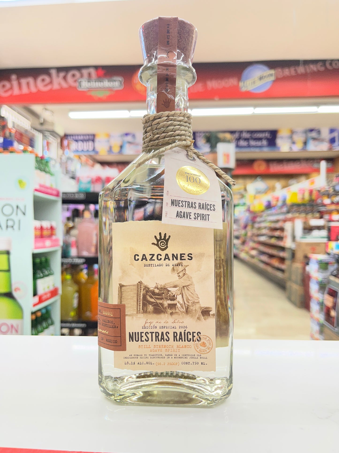 Cazcanes tequila Nuestra Raices Batch 2 bottle on a shelf with colorful product packaging in the background in Sacramento, California.