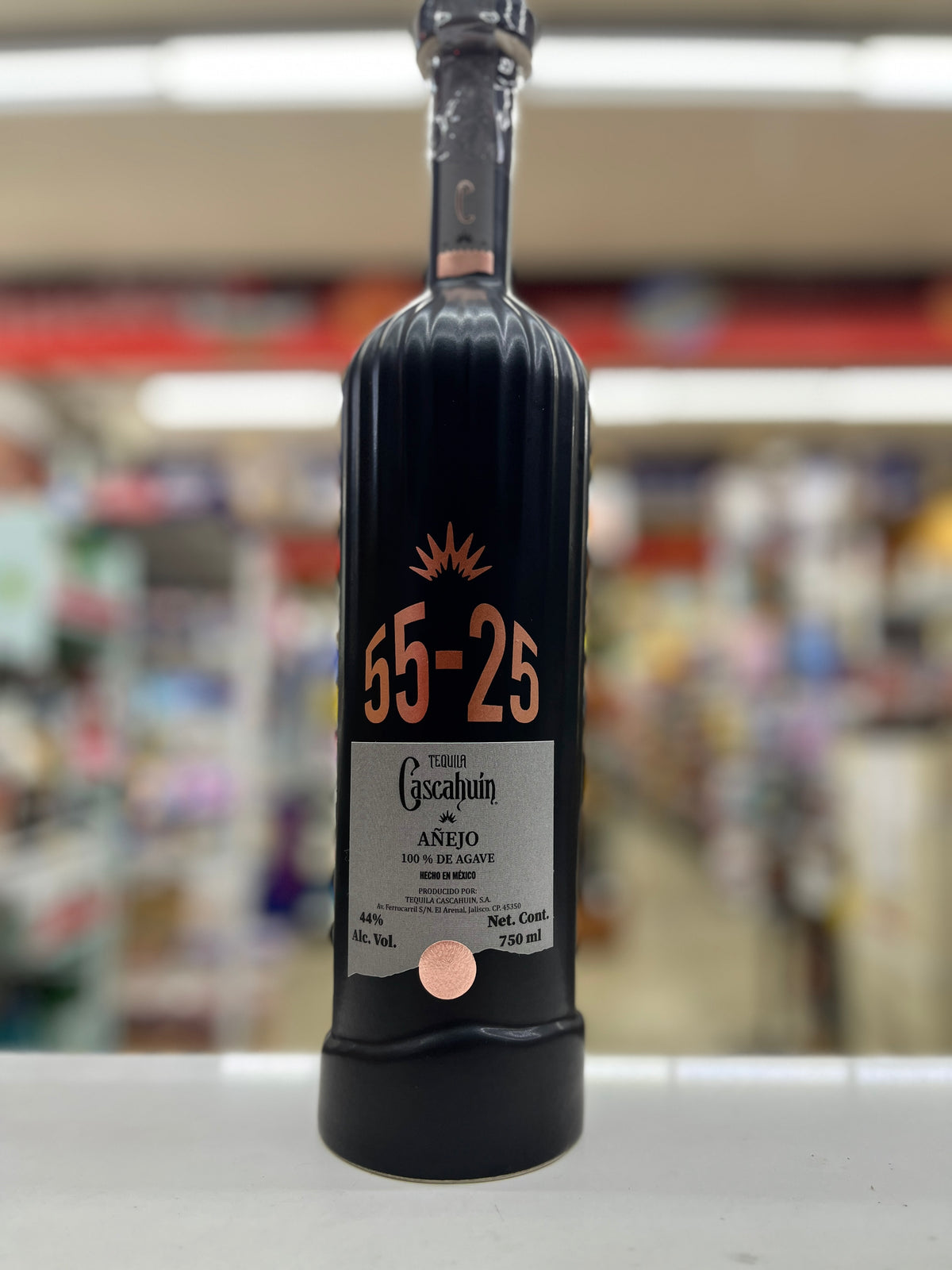a bottle of Caschuin Anejo 55-25 Edition sitting on a shelf with blurred background at a store in East Sacramento, California.