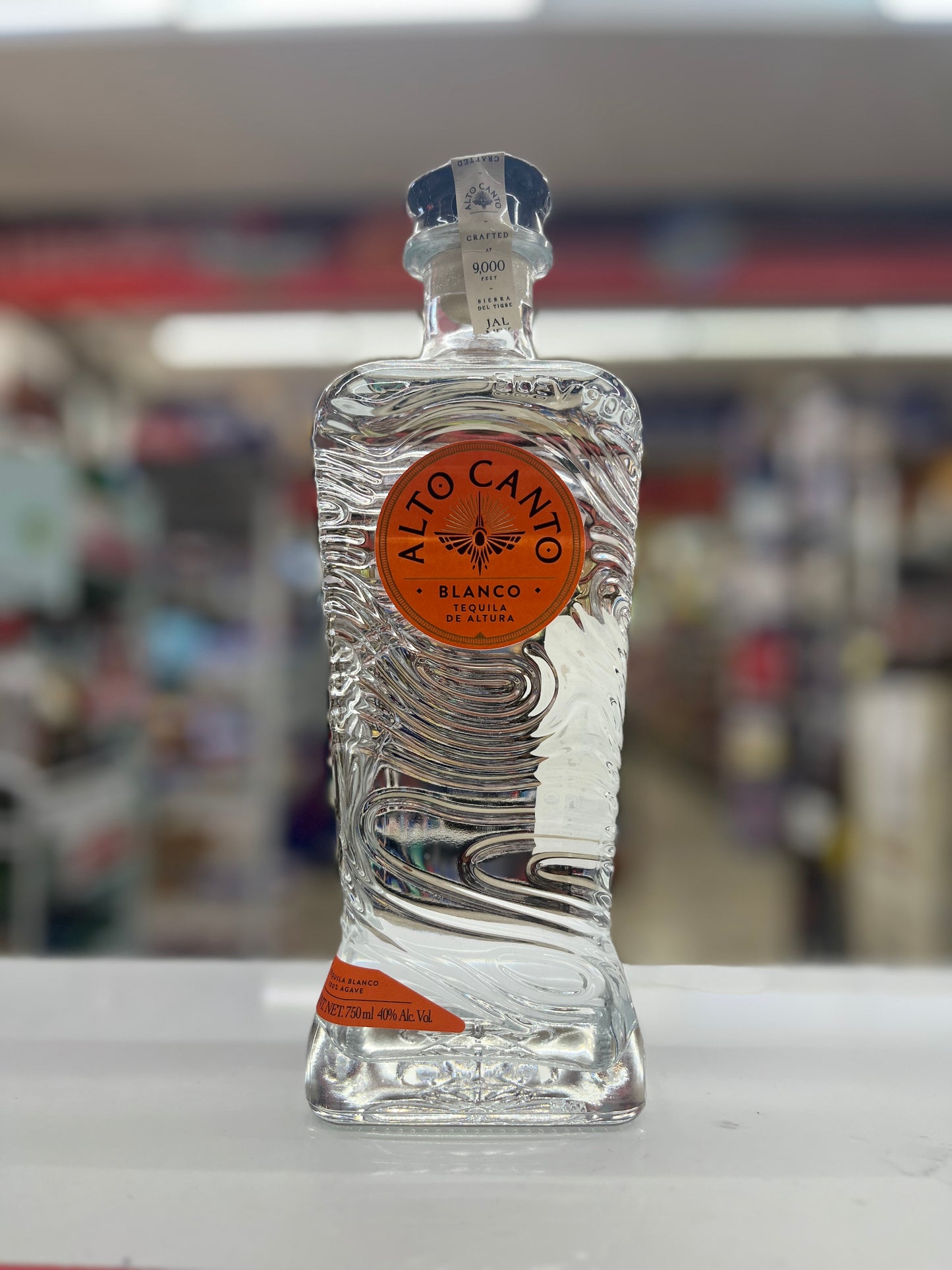 Alto Canto Tequila Blanco rested on a white counter with blurred background.