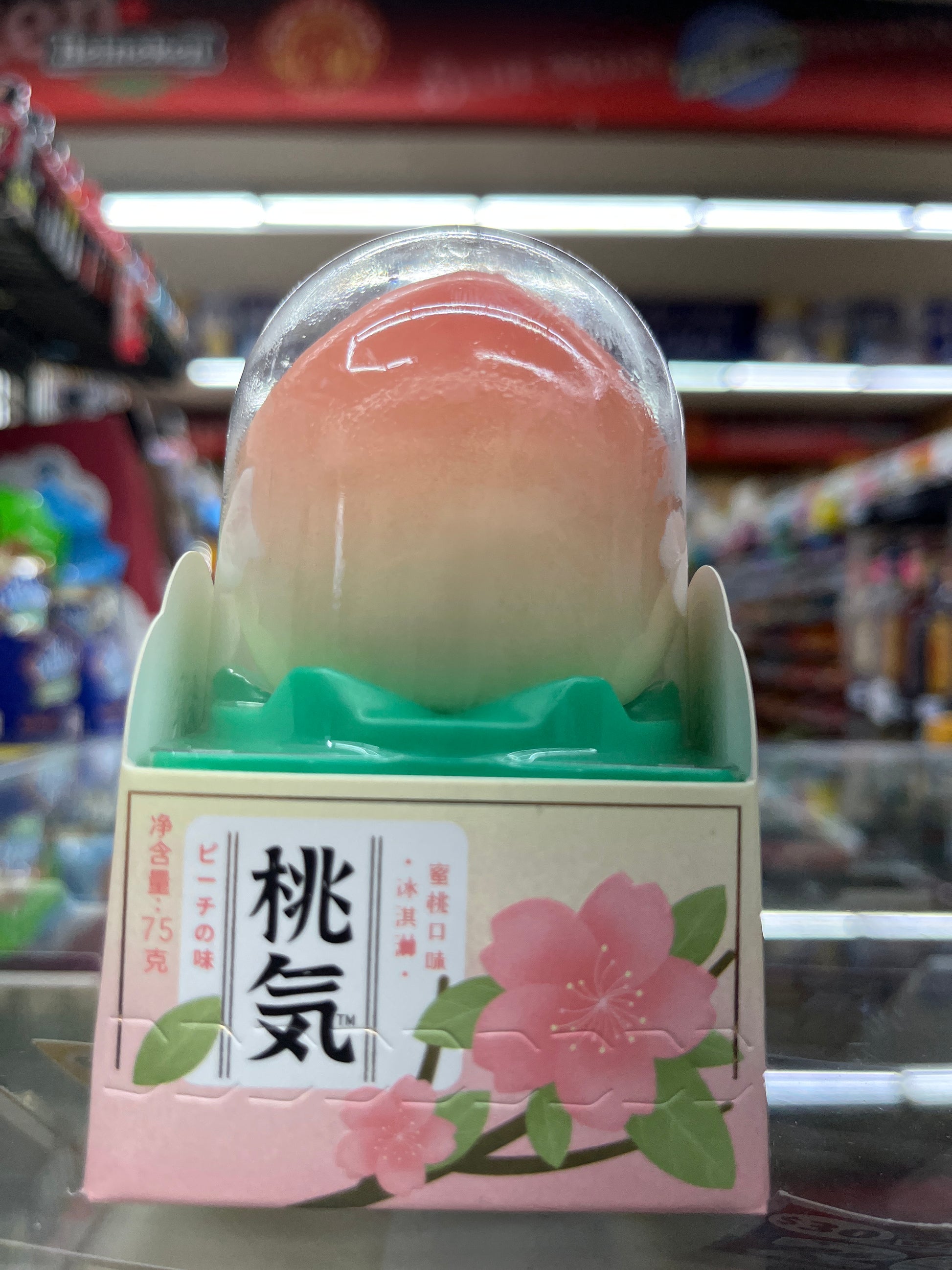 Peach-shaped product with a floral packaging design on a blurred background, Hong Ki Peach Flavored Ice cream, Korean ice cream, Front Side