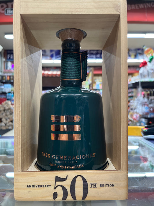 Bottle of Tres Generaciones anejo tequila in a wooden box with '50th Anniversary' text, blurred bar background