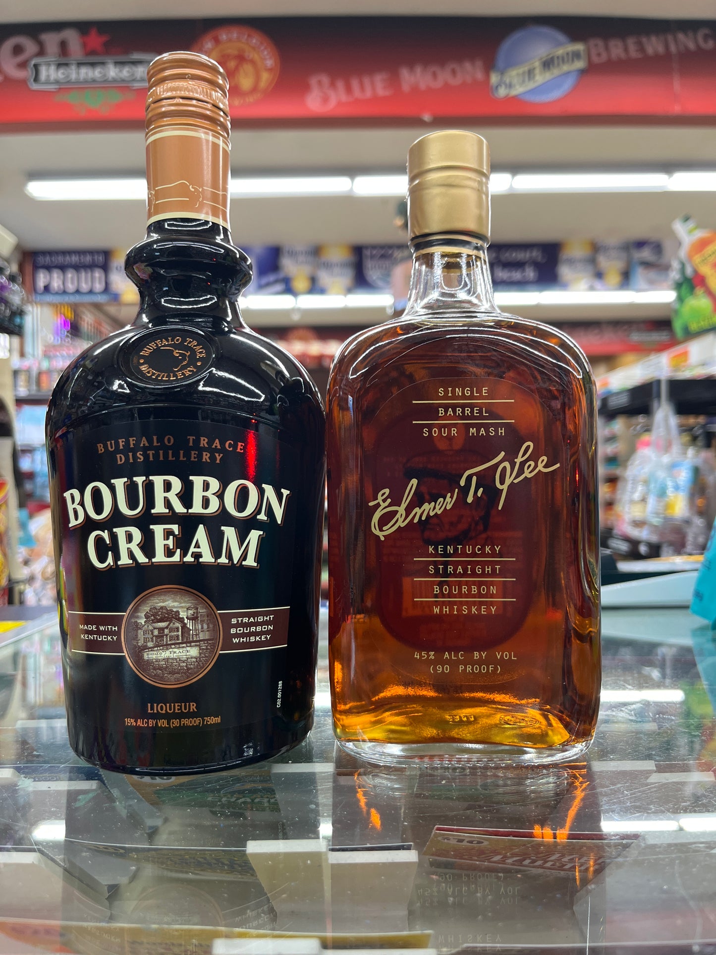 a bottle of Elmer t lee Kentucky straight bourbon sitting on a shelf along with a bottle of Buffalo trace Bourbon Cream