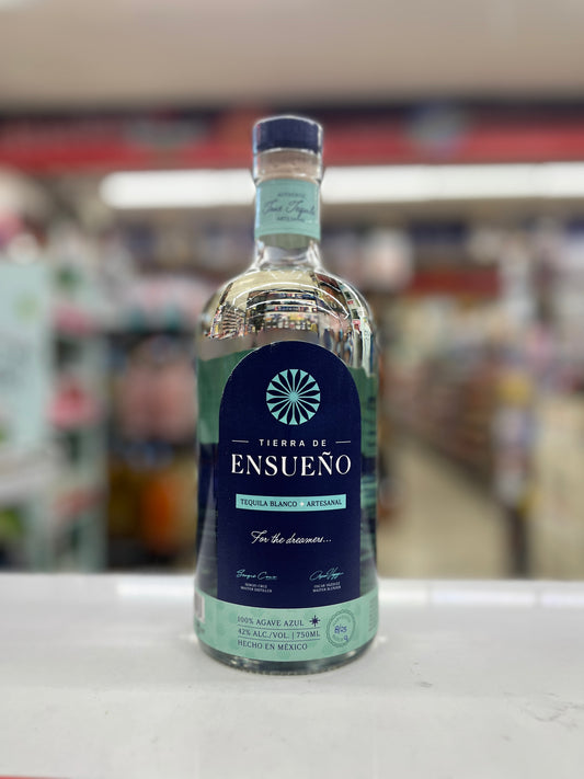 A bottle of Ensueño Tequila Blanco on a white countertop in a blurred retail store setting.
