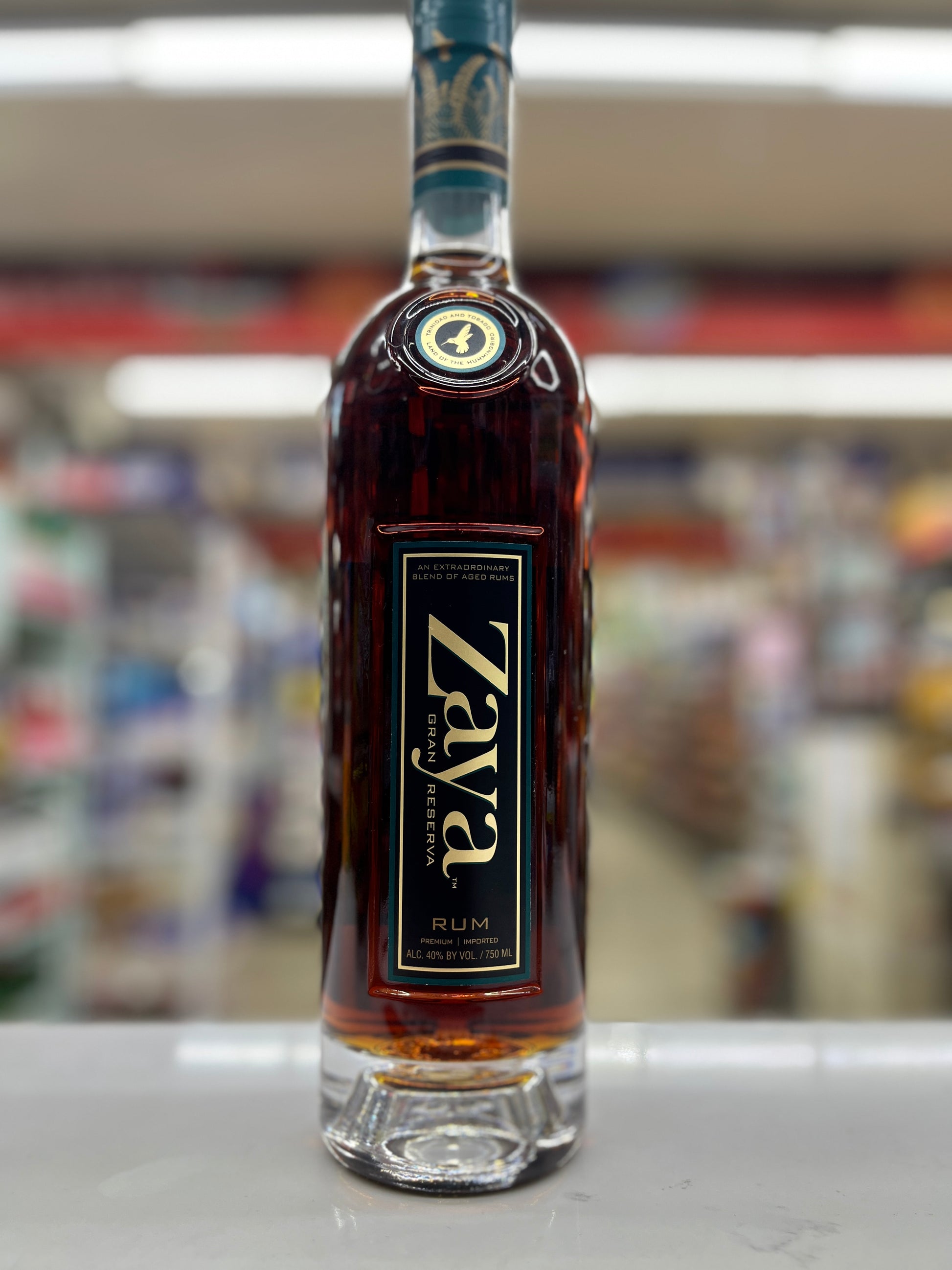 A bottle of Zaya Gran Reserva Rum standing on a white counter in a blurred retail store environment.