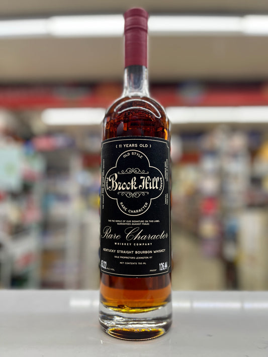 A bottle of Brookhill Rare Character 11 Years Old bourbon whiskey, featuring a black label and a dark red wax seal, standing on a white shelf against a blurred store background.