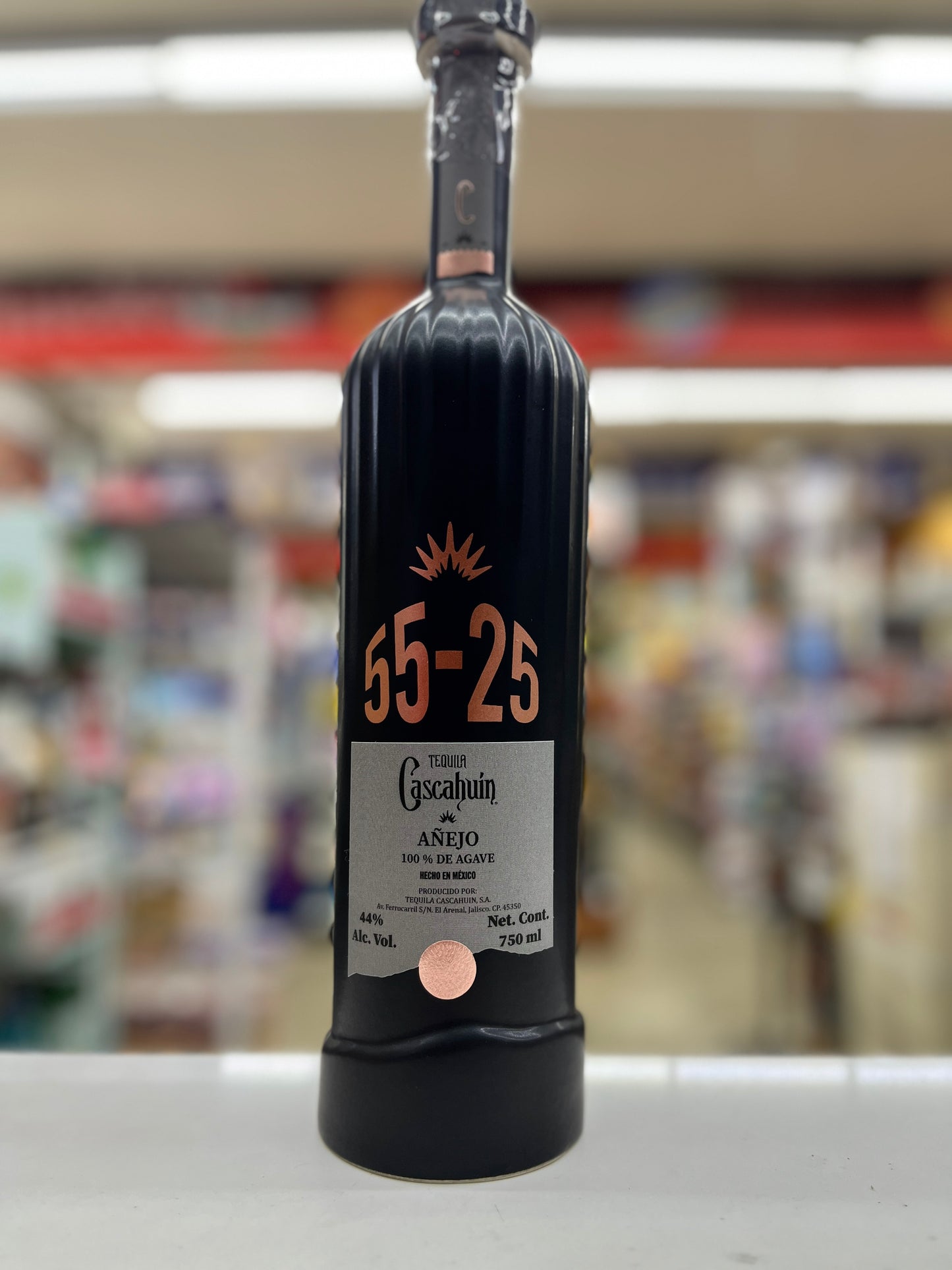 a bottle of Caschuin Anejo 55-25 Edition sitting on a shelf with blurred background at a store in East Sacramento, California.