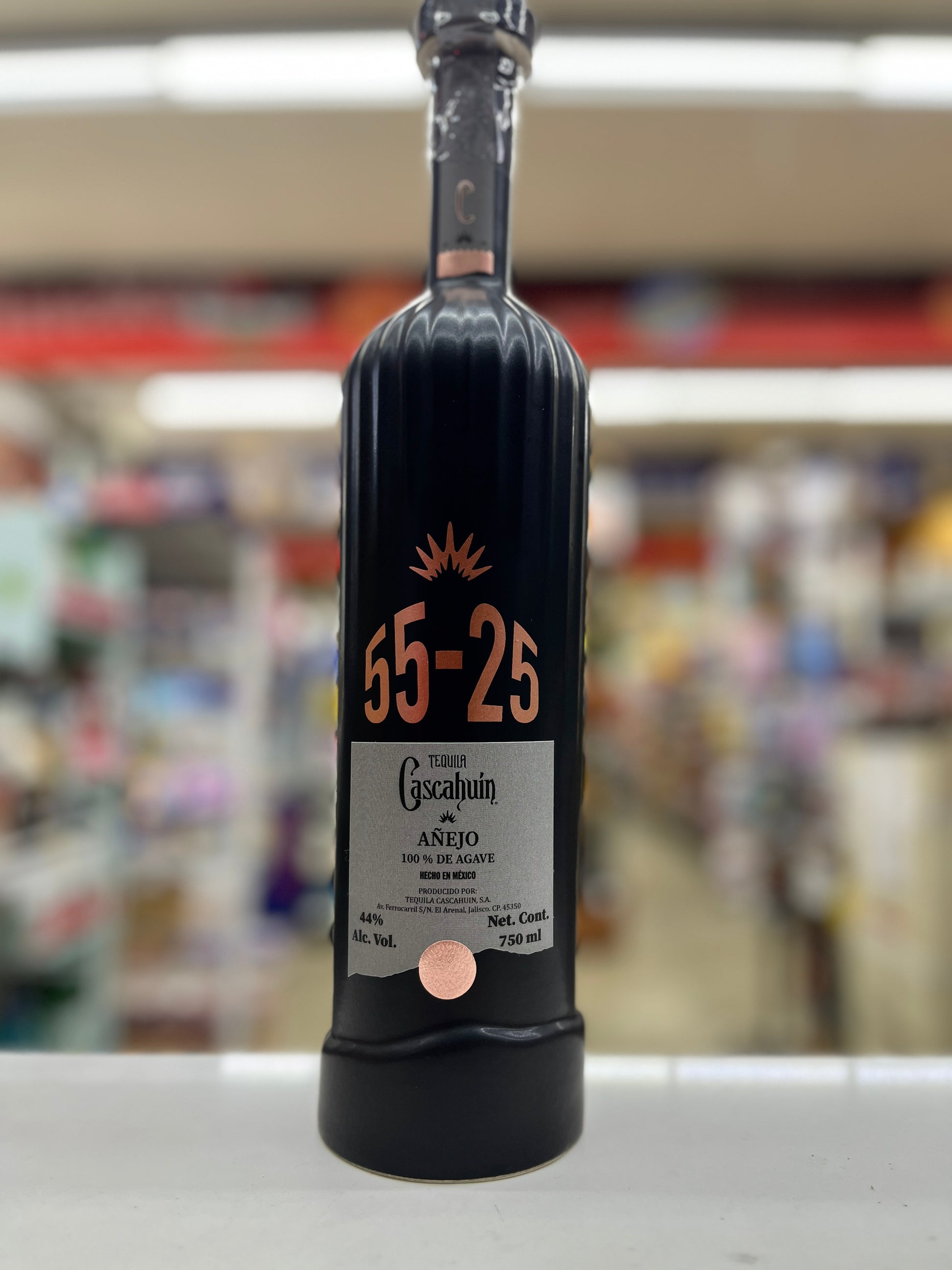 a bottle of Caschuin Anejo 55-25 Edition sitting on a shelf with blurred background at a store in East Sacramento, California.