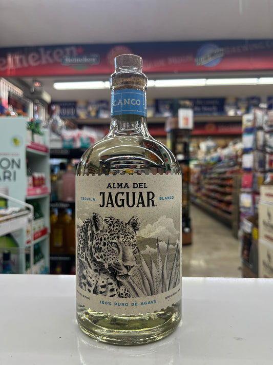 A bottle of Alma Del Jaguar Blanco tequila with a detailed jaguar label, displayed on a white counter inside a retail store.