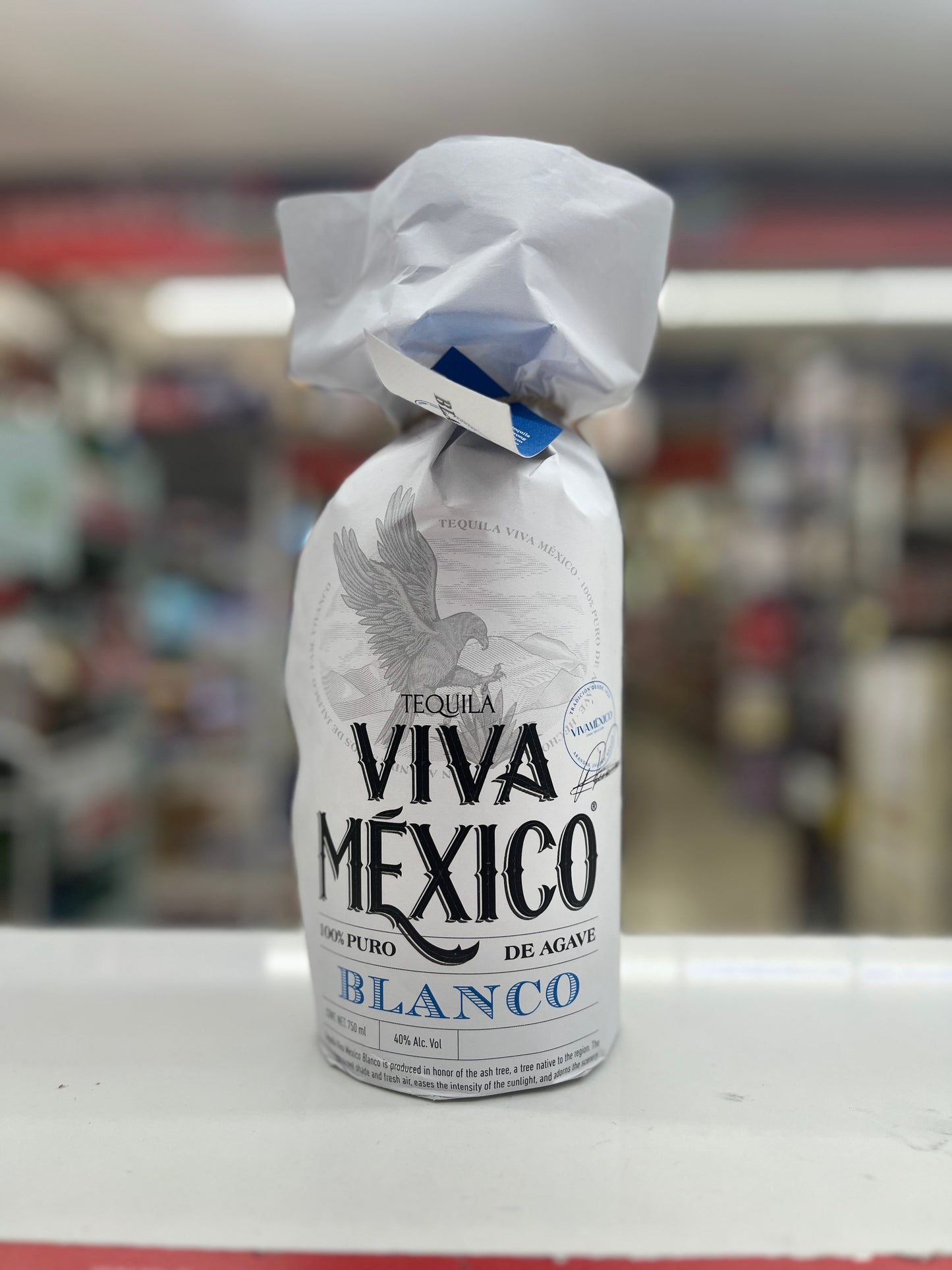 a bottle of Viva Mexico Blanco Tequila wrapped in a white paper.