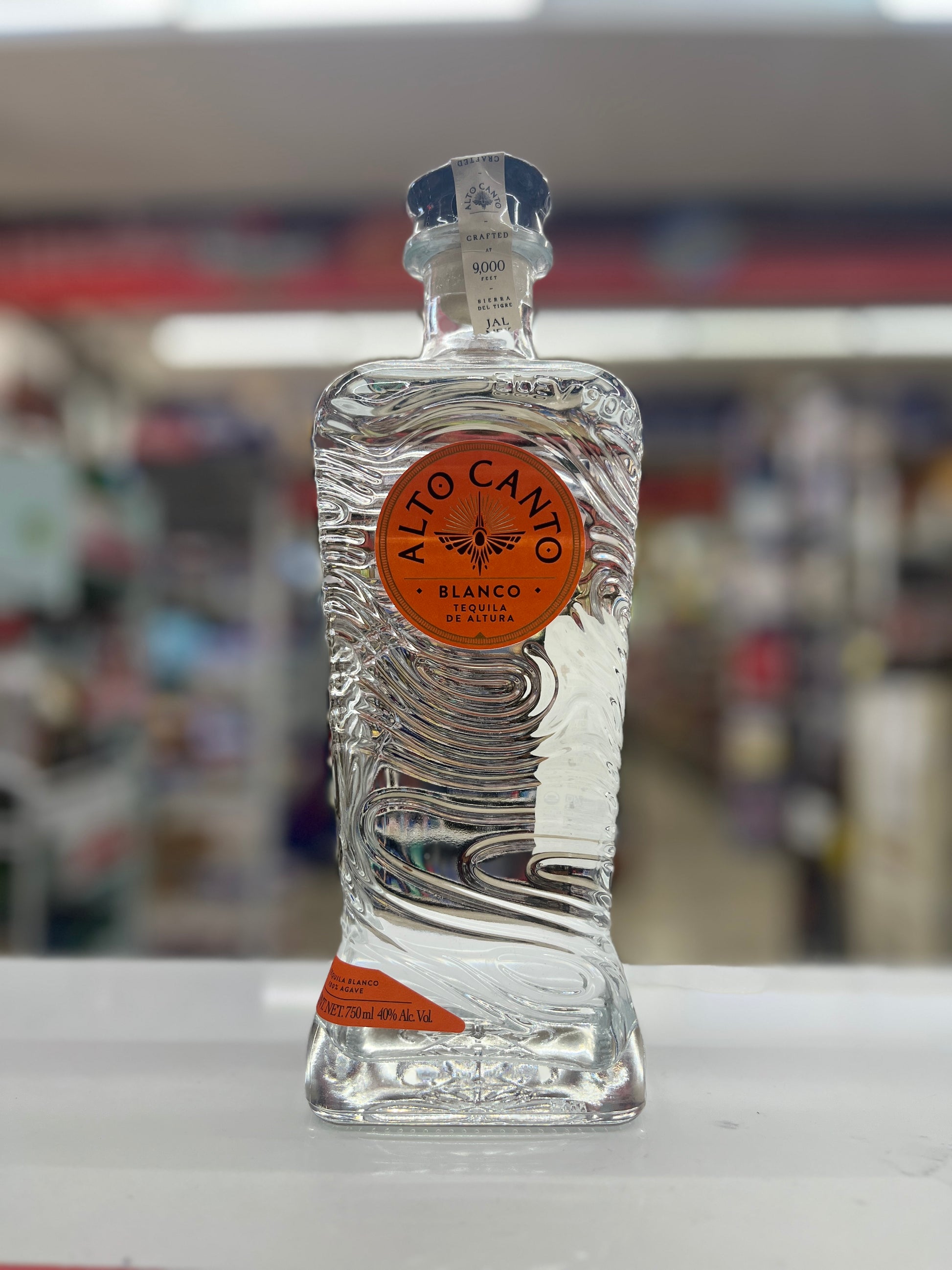 Alto Canto Tequila Blanco rested on a white counter with blurred background.