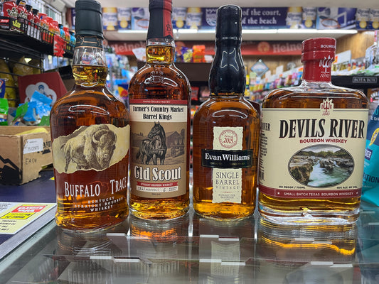 Four bottles of whiskey on a store shelf with various products in the background
